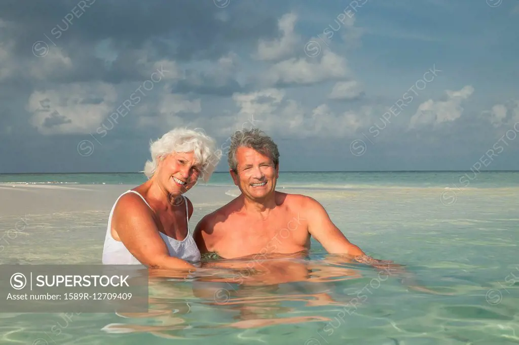 Older Caucasian couple swimming on beach