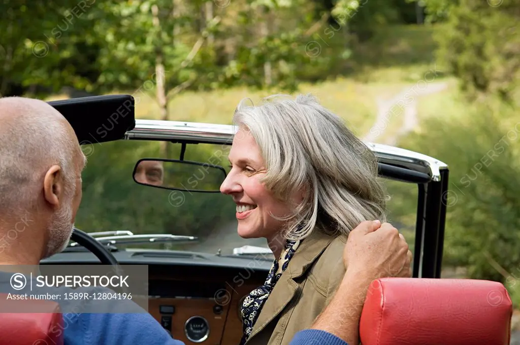 Rear view of older couple driving convertible