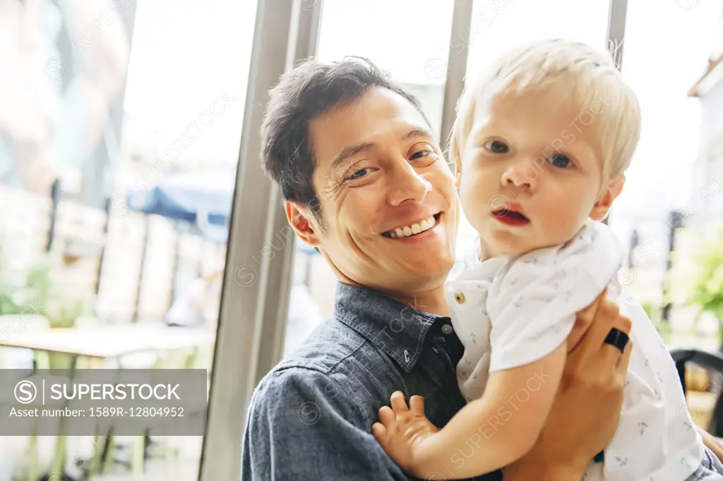 Smiling father holding son by window