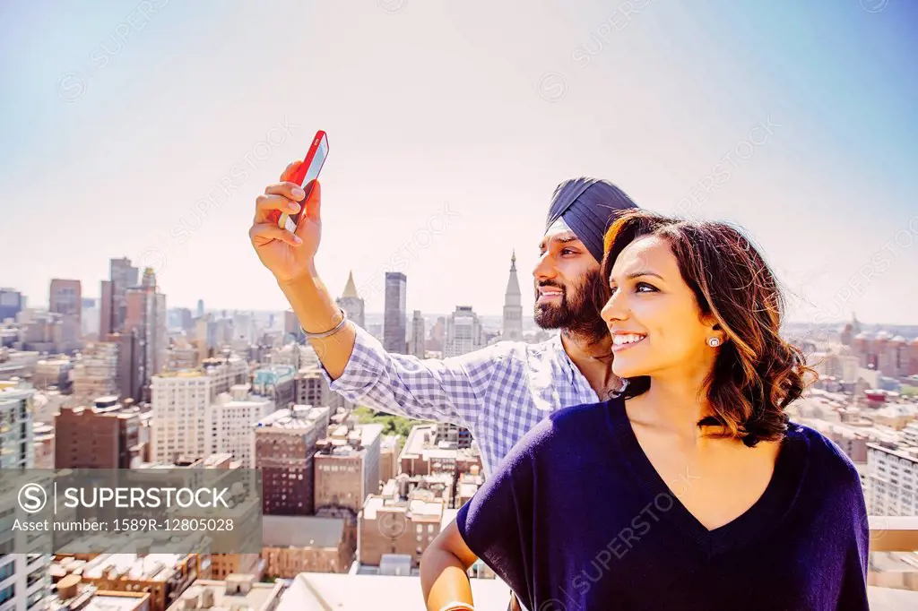 Indian couple taking selfie over New York cityscape, New York, United States