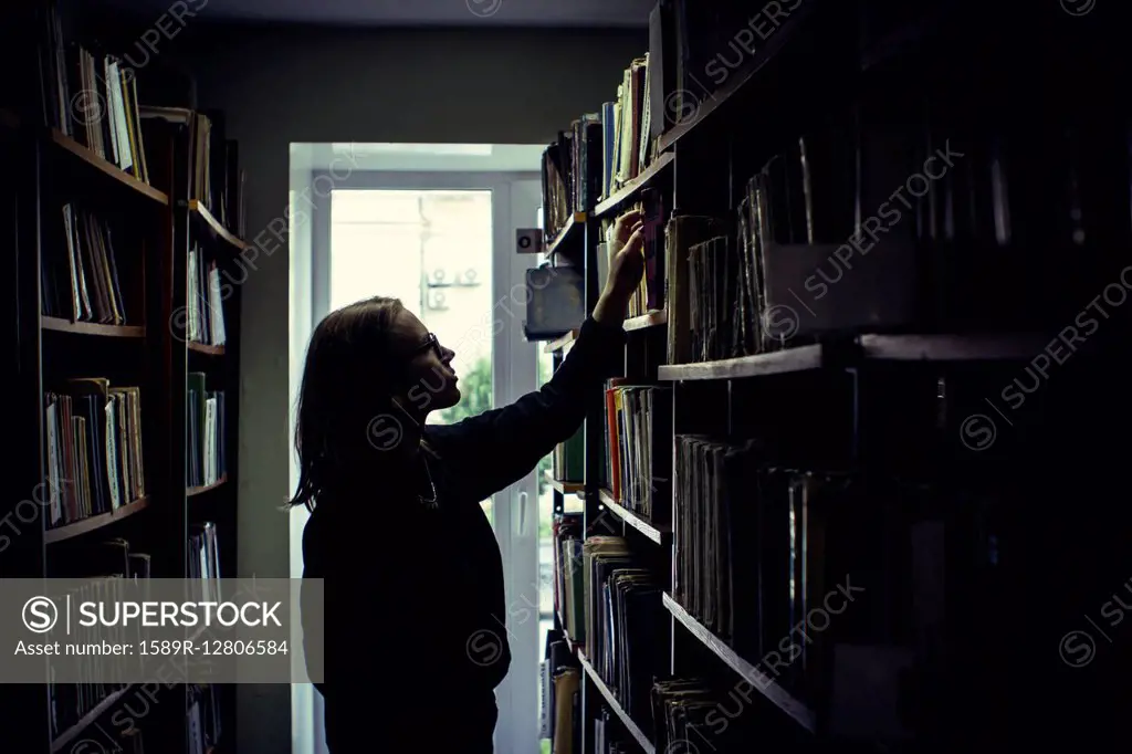 Caucasian woman searching for book in library