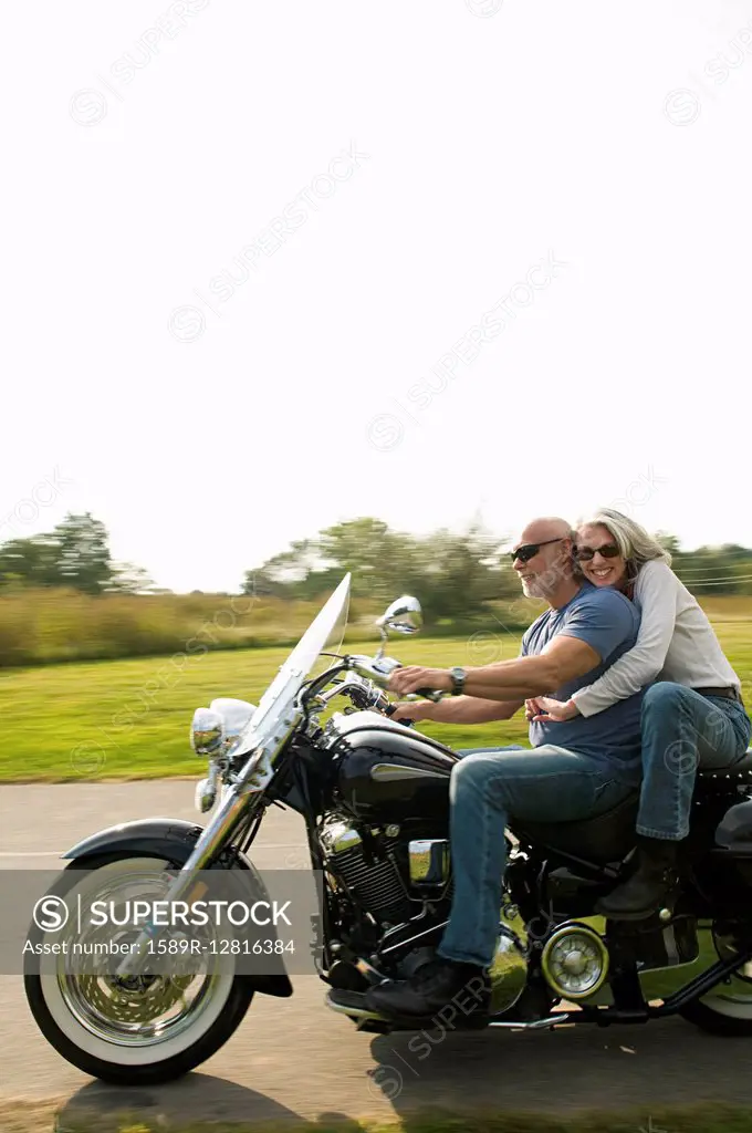 Older couple riding motorcycle on rural road