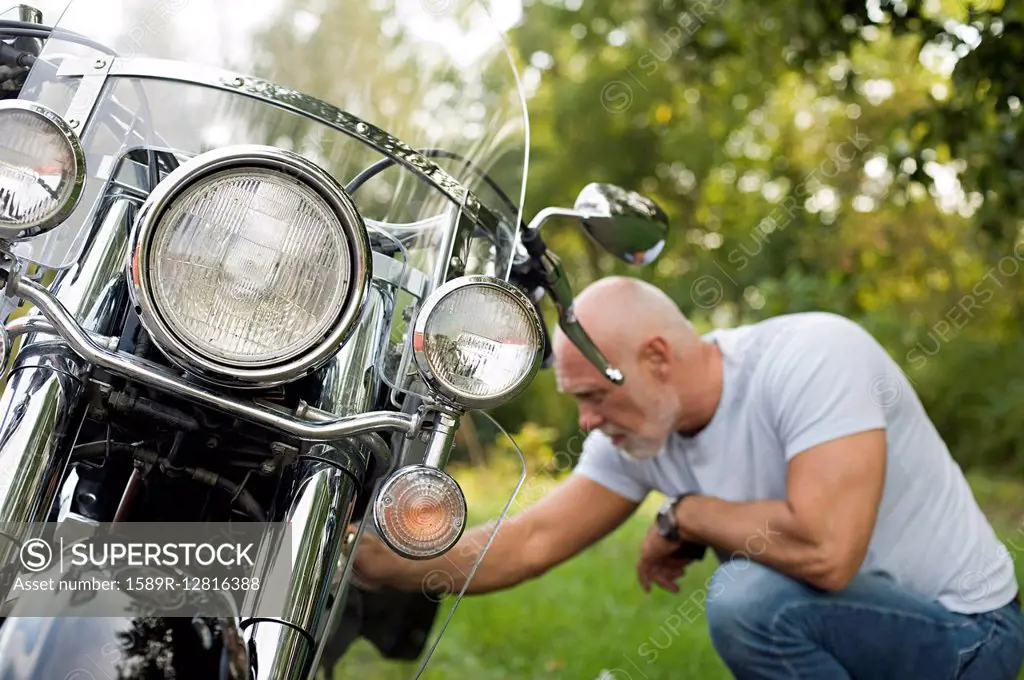 Older man repairing motorcycle in park