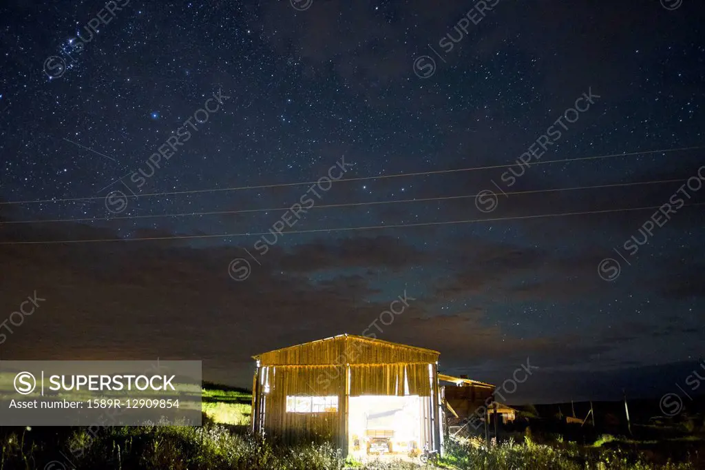 Illuminated cabin under starry night sky