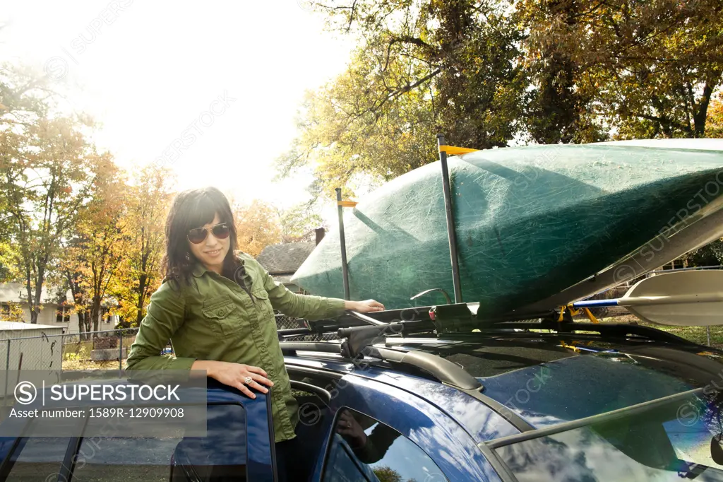 Caucasian woman packing kayak on car