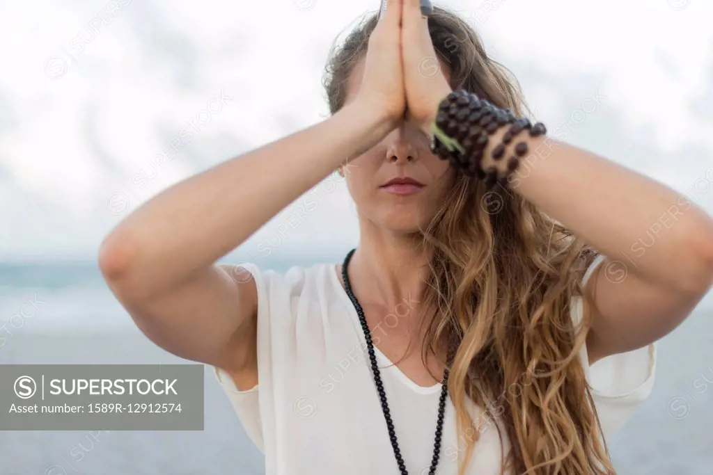 Hispanic woman meditating on beach