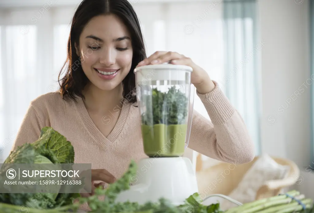 Hispanic woman blending healthy smoothie