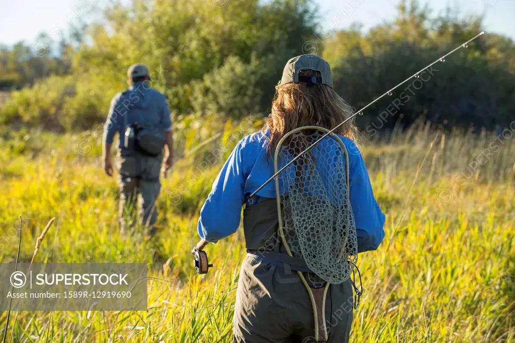 Caucasian couple with fishing gear in field