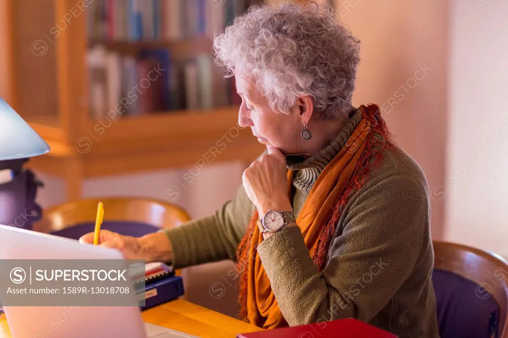 Older mixed race woman writing in library