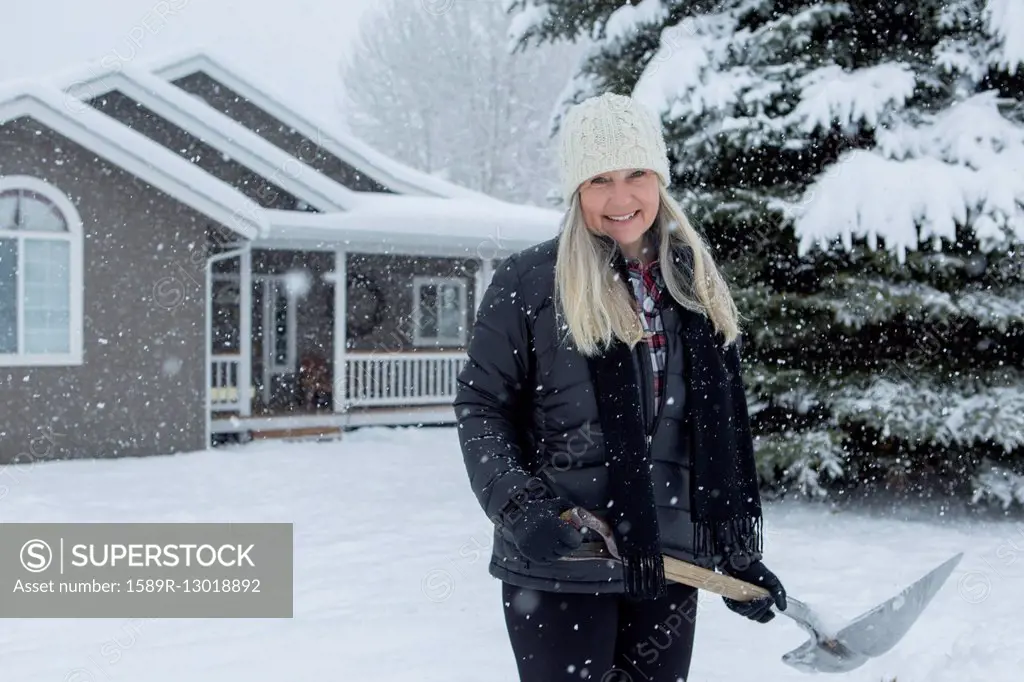 Older Caucasian woman shoveling snow in front yard