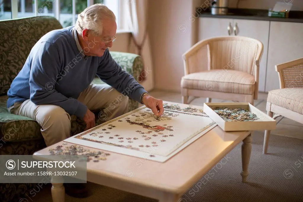 Older man on sofa solving jigsaw puzzle