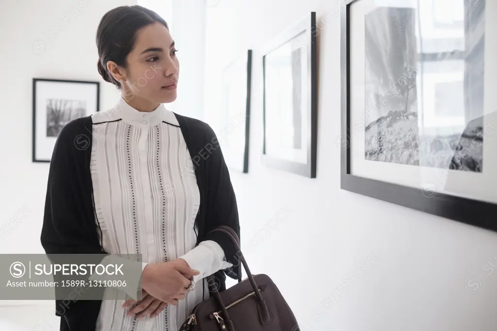 Hispanic woman admiring art in gallery