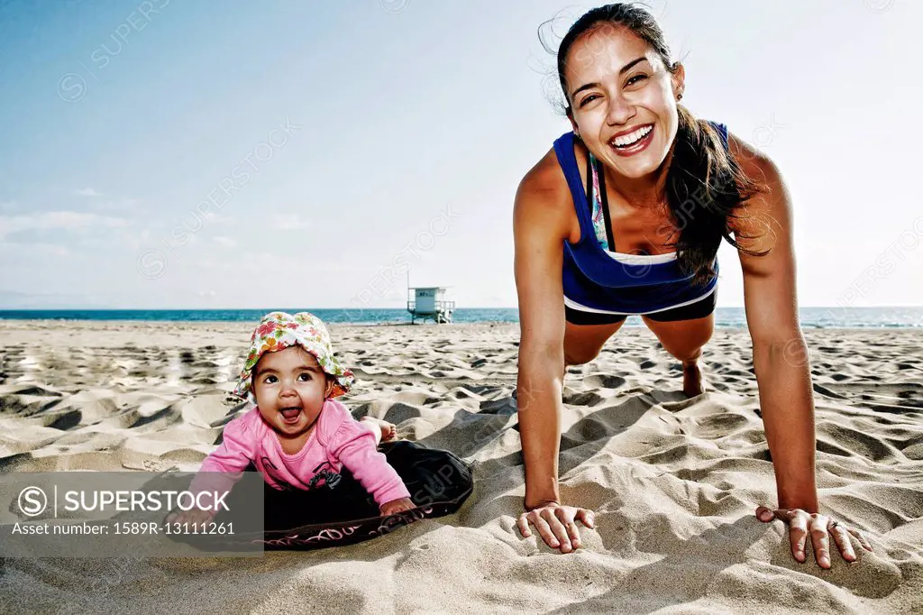 Mother and daughter doing push-ups at beach