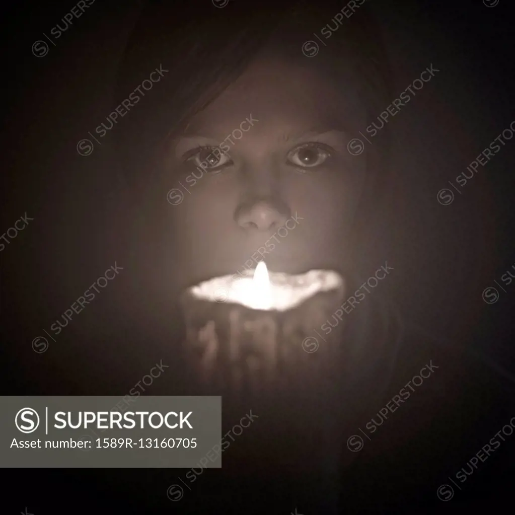 Caucasian woman holding candle near face
