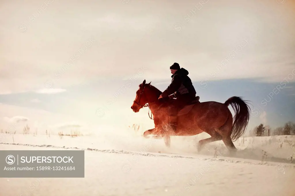 Caucasian man riding horse in snowy landscape