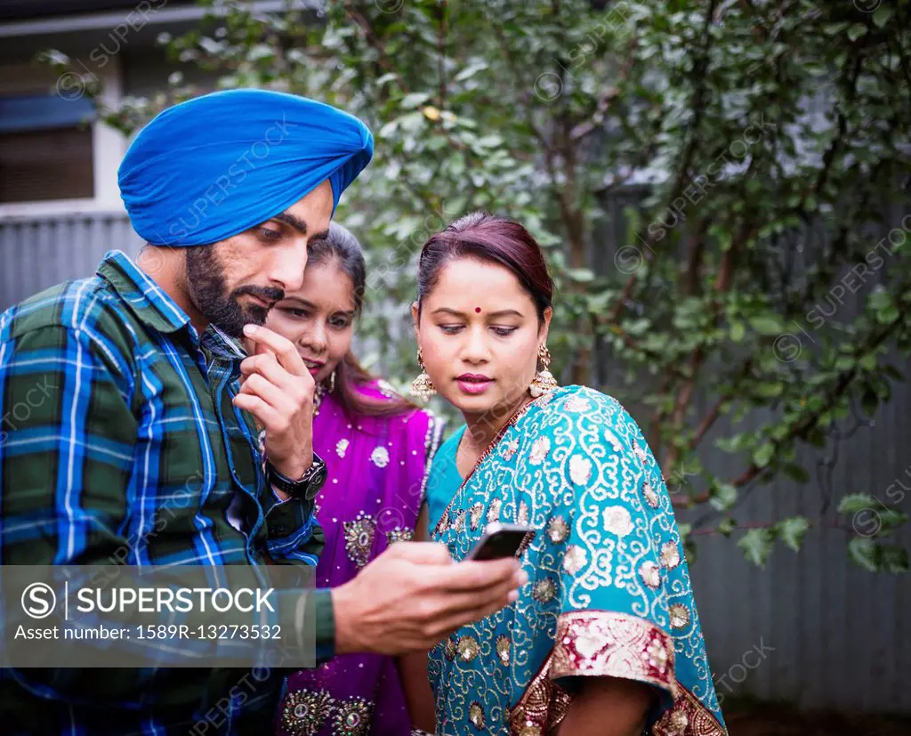 Family in traditional Indian clothing using cell phone