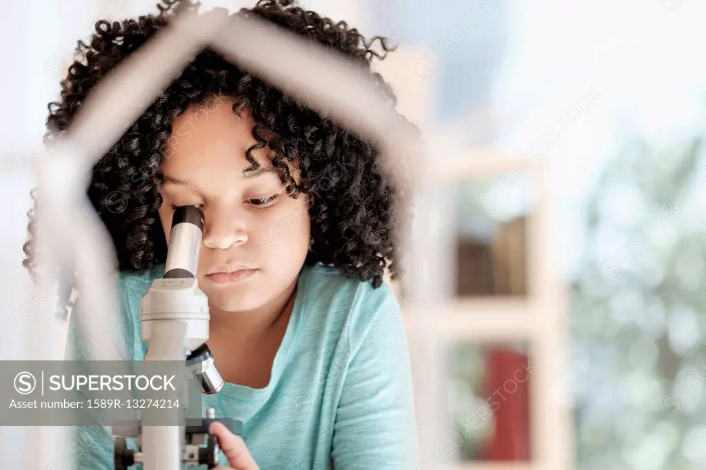 African American girl using microscope in science classroom