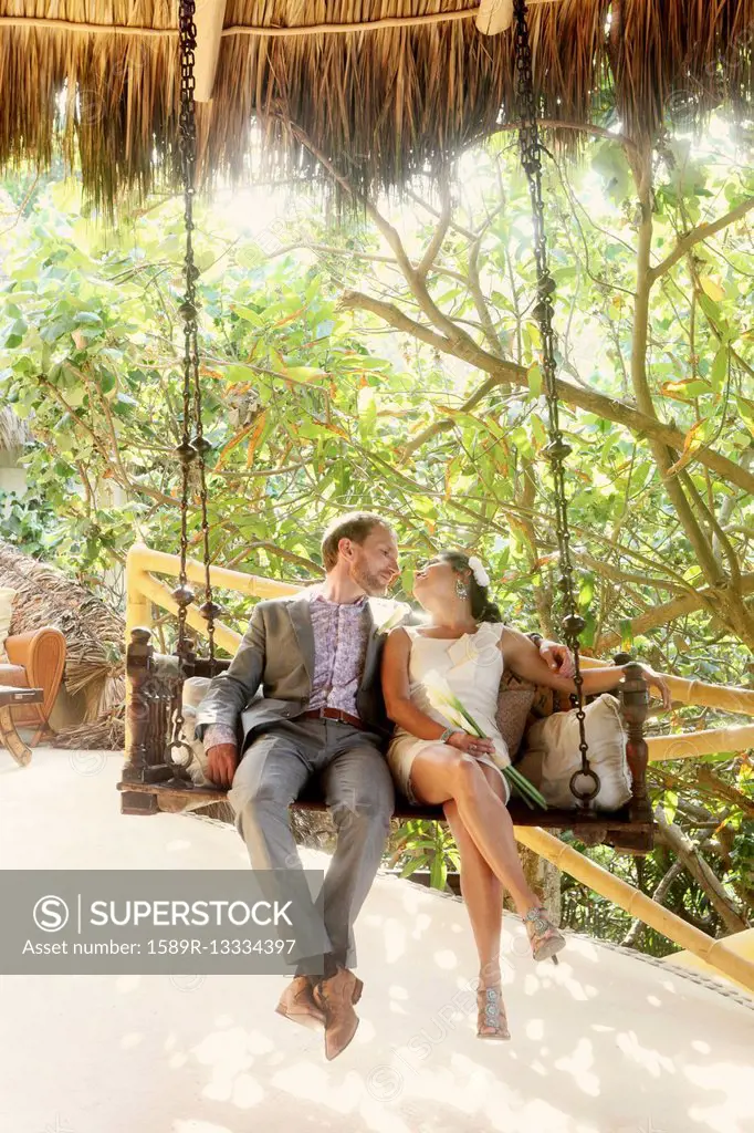 Newlywed couple sitting on swing together