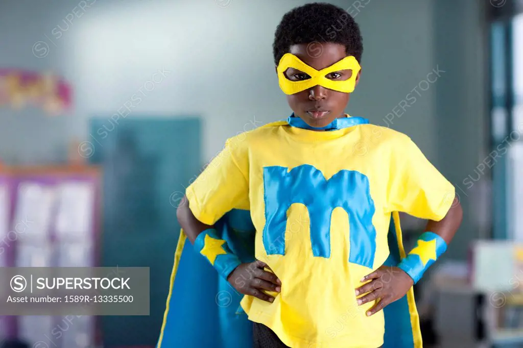 African American boy wearing superhero costume in classroom