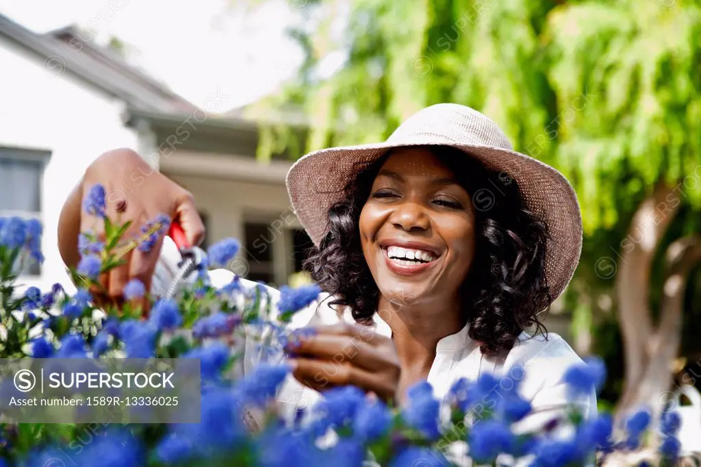 Smiling woman pruning flowers in garden