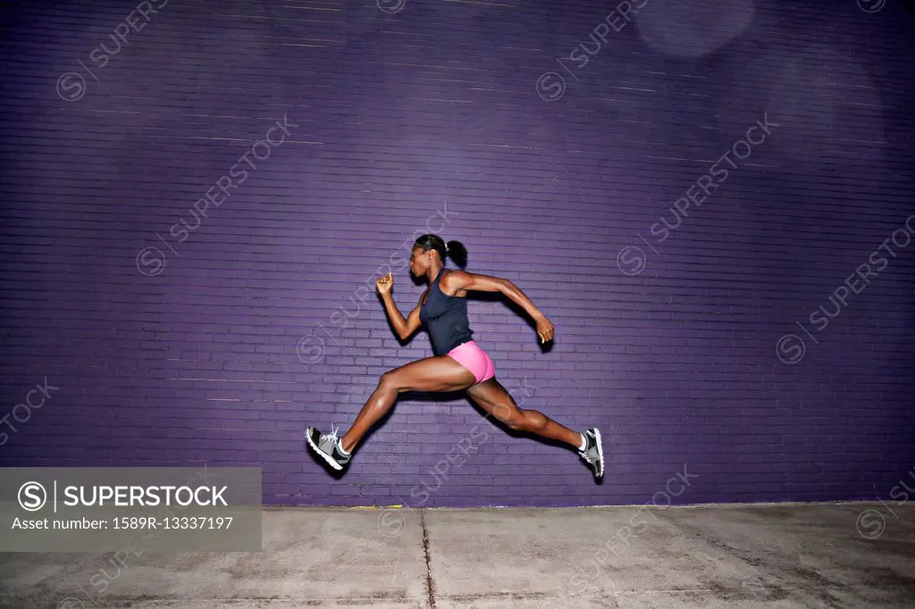 Female athlete running on sidewalk