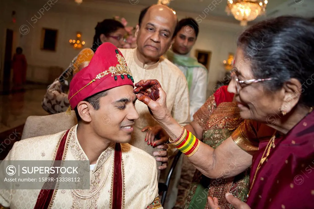 Indian woman marking groom's face