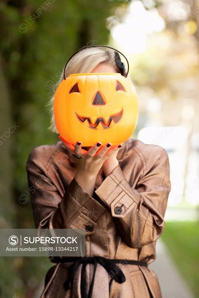 Caucasian woman holding jack o' lantern bucket