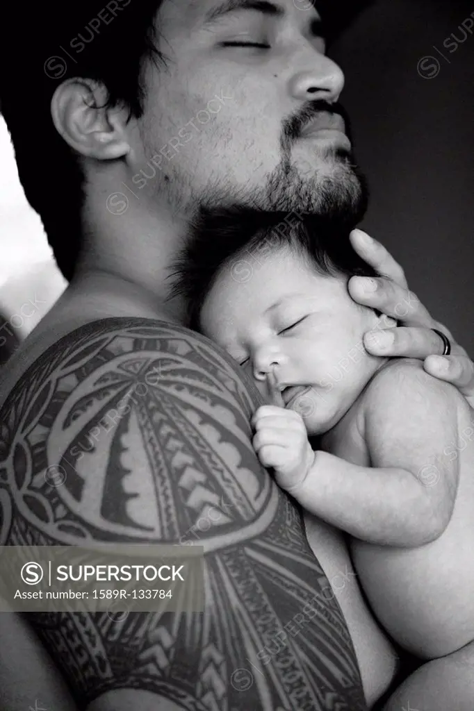 Tattooed father holding newborn baby