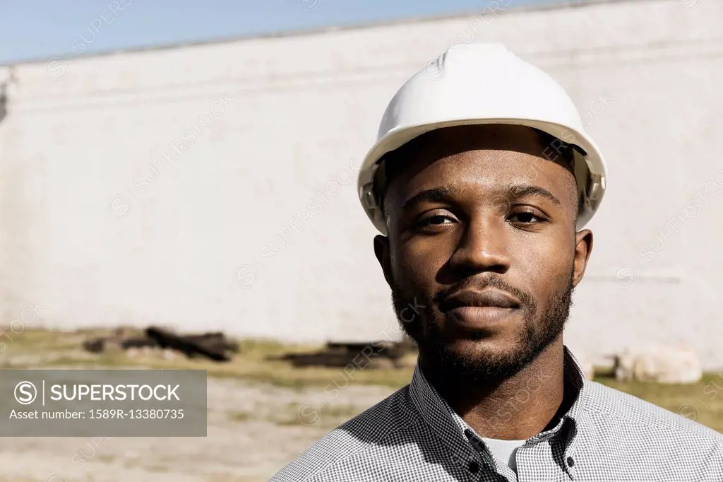 Close up portrait of Black man wearing hard-hat at construction site