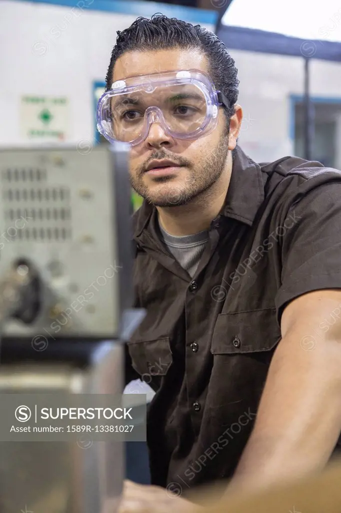 Hispanic worker operating machinery in factory