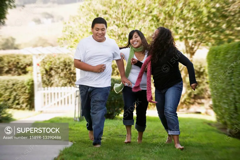 Hispanic siblings running on grass