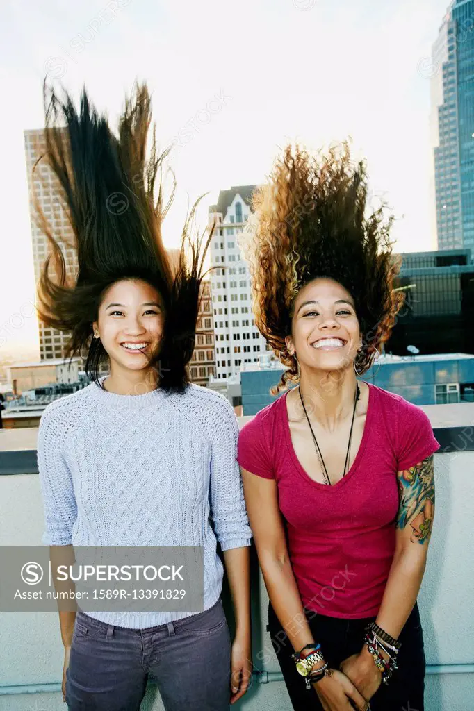 Women tossing their hair on urban rooftop