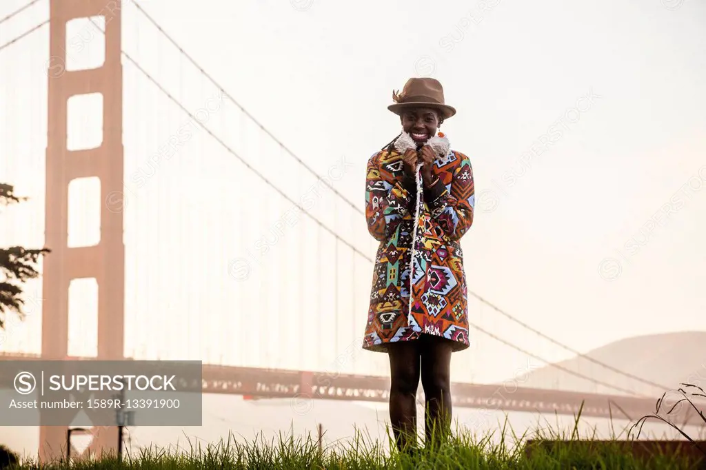 Black woman wearing colorful coat by Golden Gate Bridge, San Francisco, California, United States
