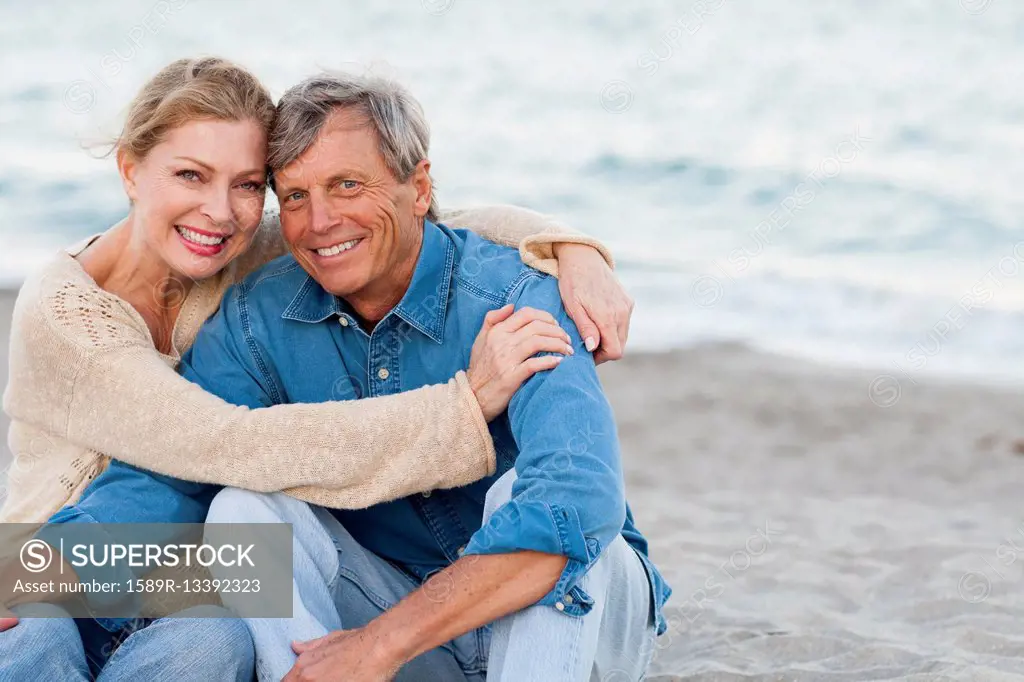 Older Caucasian couple hugging on beach