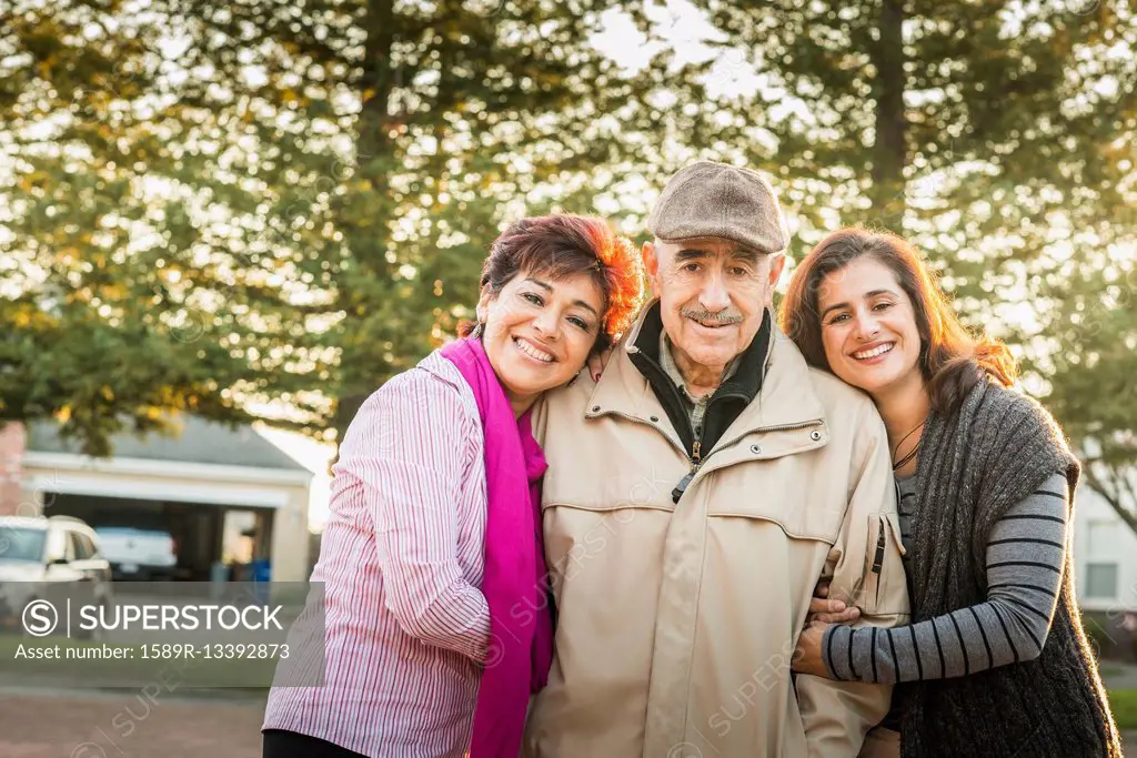 Hispanic parents and daughter smiling outdoors