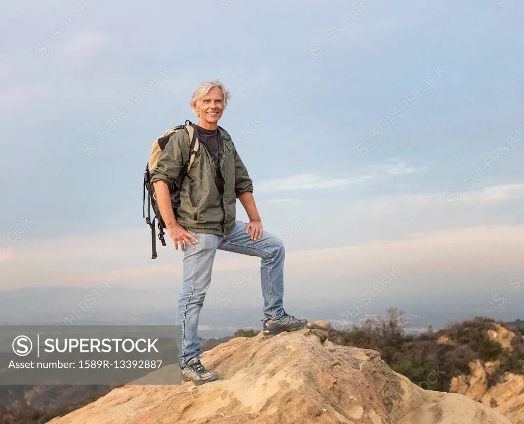 Older Caucasian man standing on rocky hilltop