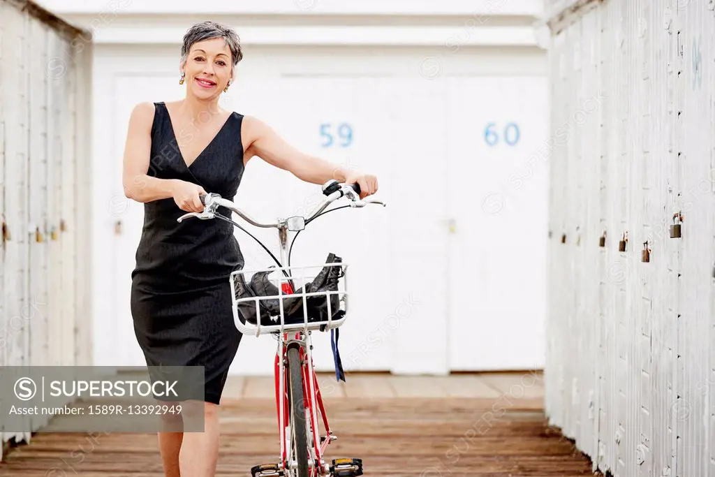 Older Caucasian woman walking bicycle on wooden dock