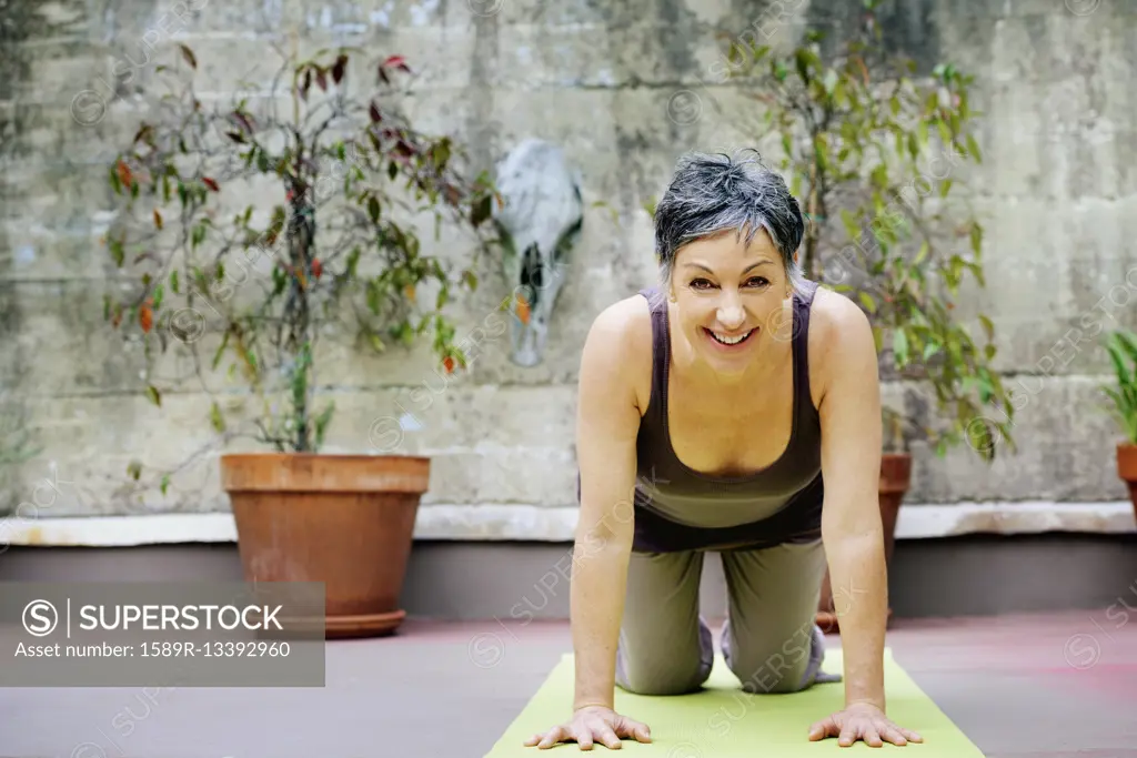 Older Caucasian woman practicing yoga in courtyard