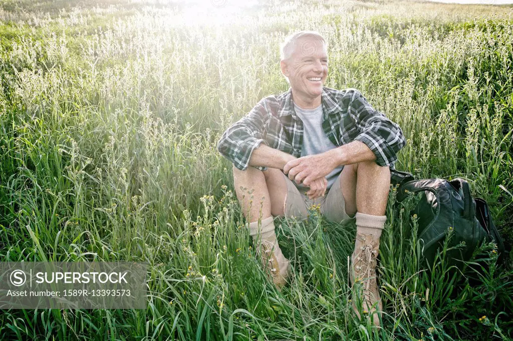 Older Caucasian man sitting on grassy hillside