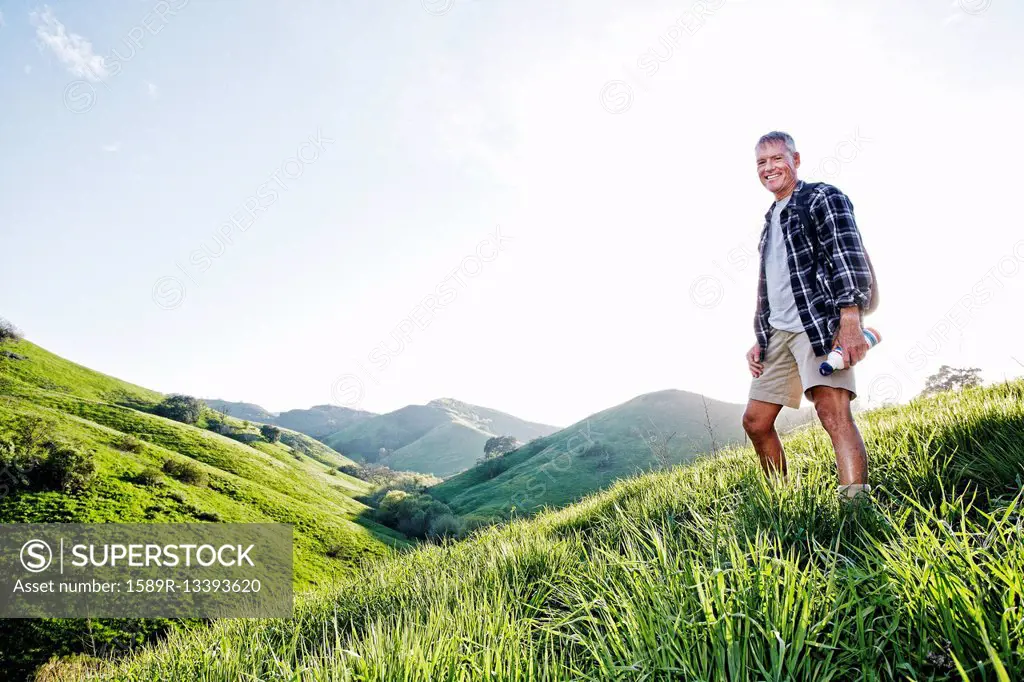 Older Caucasian man smiling on grassy hillside