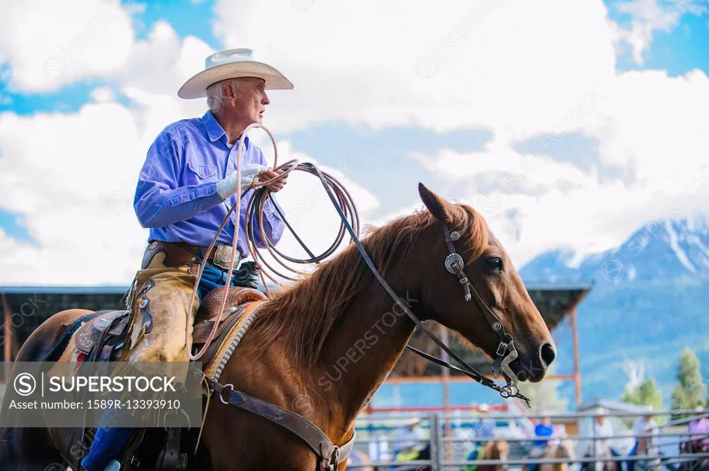 Older Caucasian cowboy riding horse at rodeo