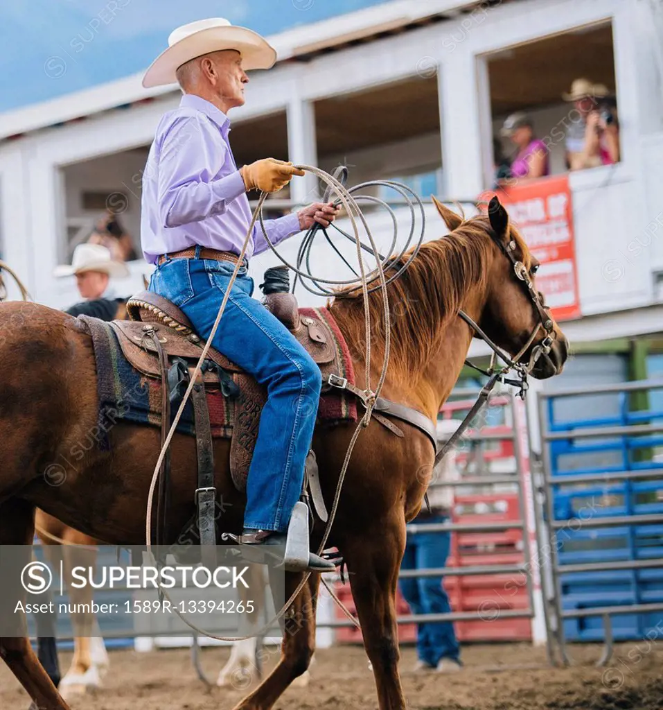 Caucasian cowboy riding horse in rodeo