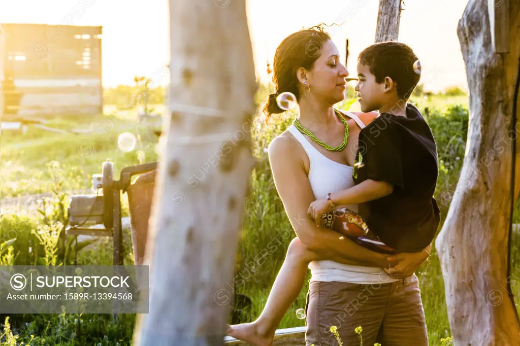 Hispanic mother carrying son in garden