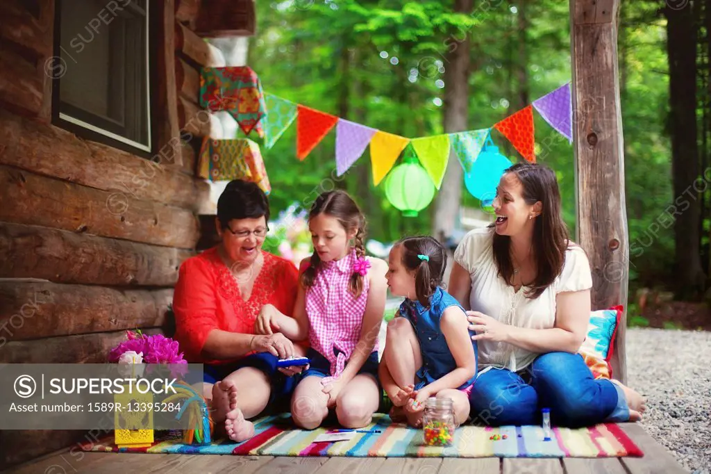 Three generations of Caucasian women playing with toy on cabin porch