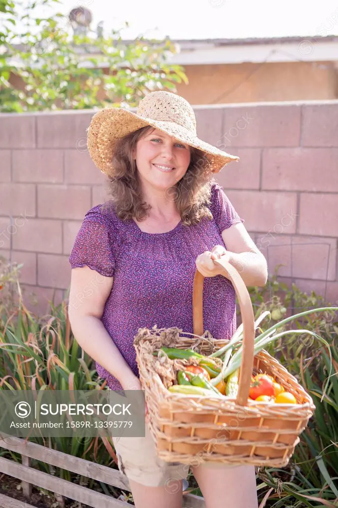 Mixed race gardener gathering vegetables in garden