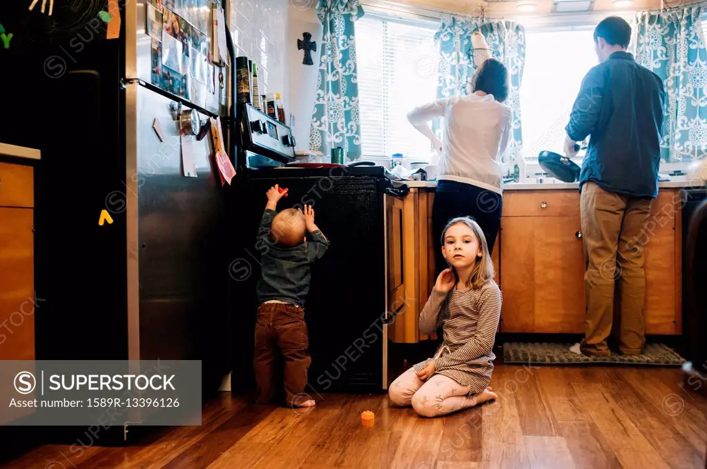 Children playing as parents cook in kitchen