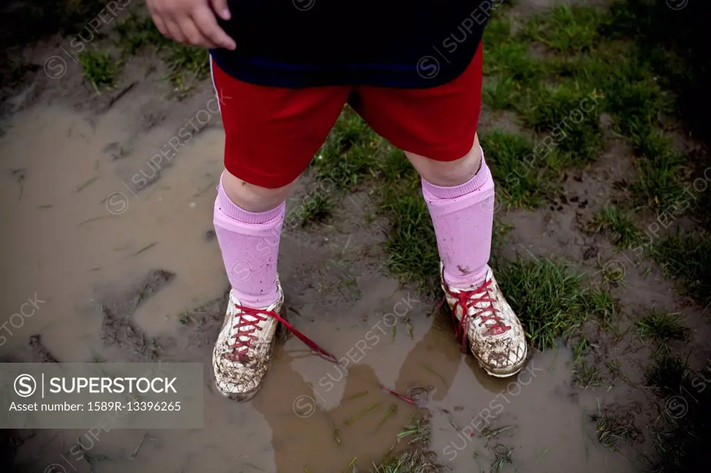 Girl wearing sneakers in mud puddle