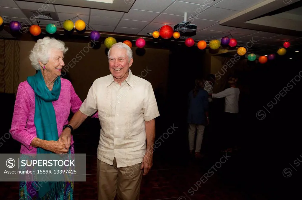 Older Caucasian couple dancing at party in retirement home