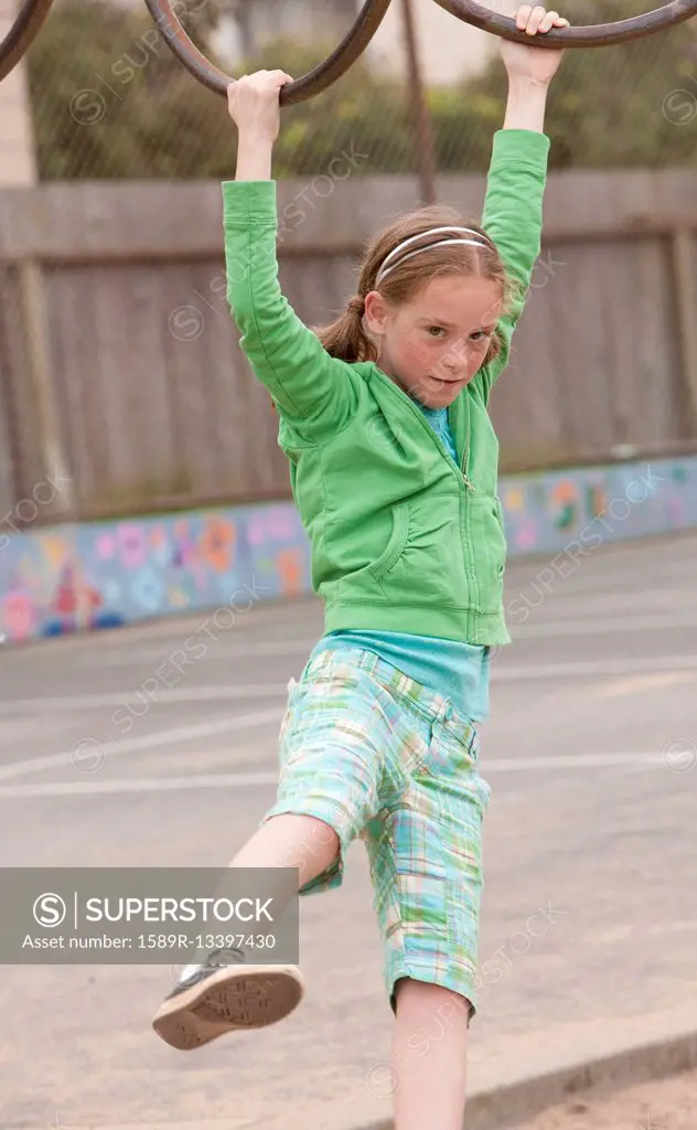 Caucasian girl playing on monkey bars at playground