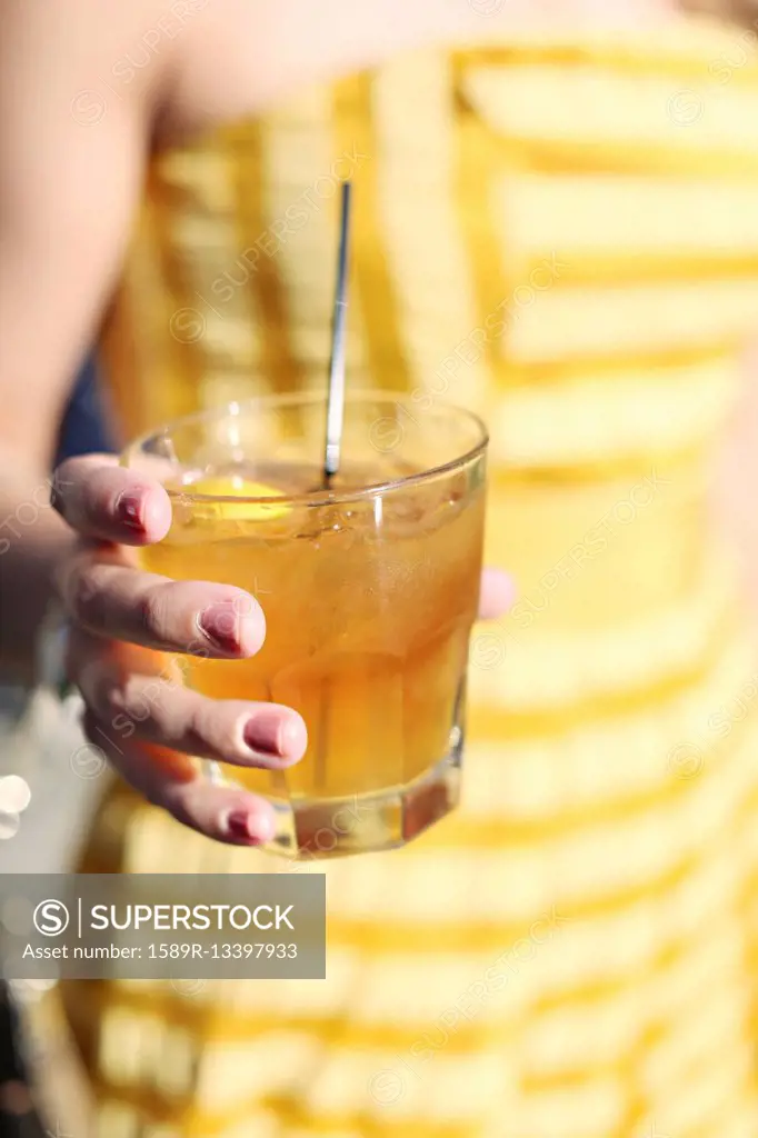 Close up of woman holding yellow cocktail drink